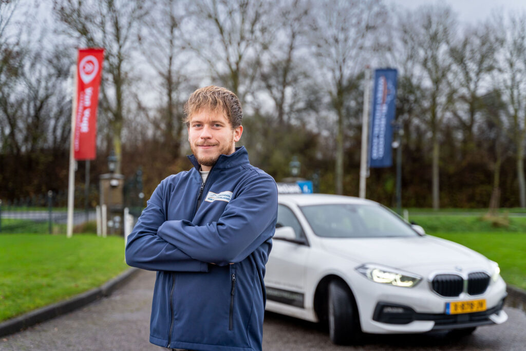 Rijinstructeur posserend voor rijlesauto